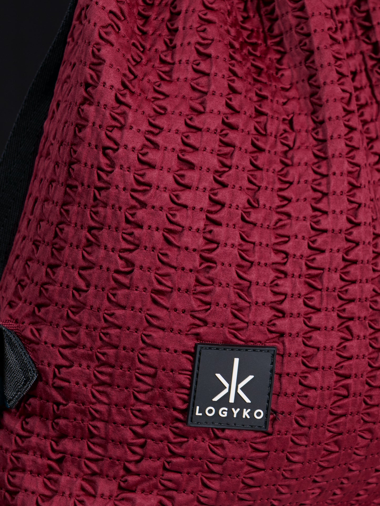 Dettaglio del logo cucito sul davanti dello Zaino Helium di LOGYKO color bordeaux